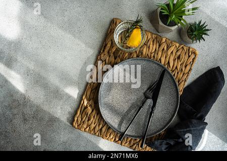 Overhead view of a place setting with a glass of lemon rosemary water on a table with houseplants Stock Photo