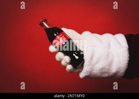 MYKOLAIV, UKRAINE - JANUARY 18, 2021: Santa Claus holding Coca-Cola bottle in hand on red background, closeup Stock Photo