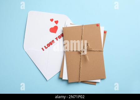 Love letter and stack of envelopes on light blue background, flat lay Stock Photo