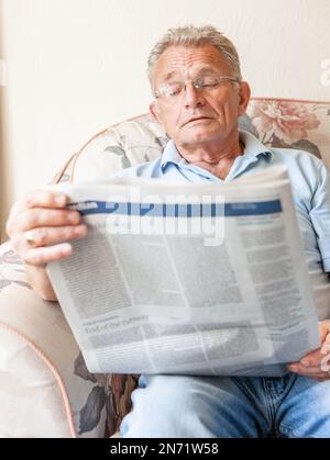 Retirement: Reading the newspaper. A senior man engrossed in his daily news as he keeps informed of current affairs. From a series of related images. Stock Photo