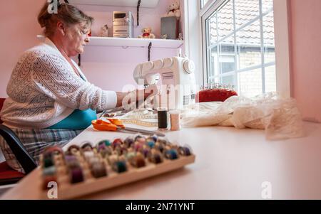 Retirement: The Seamstress. A senior woman candidly working on her sewing machine in her crafts room. From a series of related images. Stock Photo