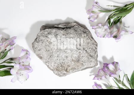 Concrete stone podium on a white gray background with hard shadows and plant, flowers. Minimal empty cosmetic product presentation scene. Geometric po Stock Photo