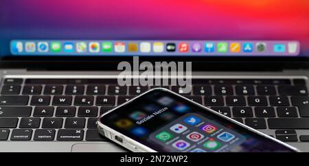Itterbeck, Germany - Feb 10 2023 Part of an open apple MacBook Pro laptop with a German Keyboard. On top lies an Iphone with Social Media tab open. Ic Stock Photo