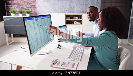 Young Businesspeople Analyzing Gantt Chart And Calendar On Computer In Office Stock Photo