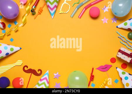 Frame of different party items and decorations with space for text on orange background, flat lay Stock Photo