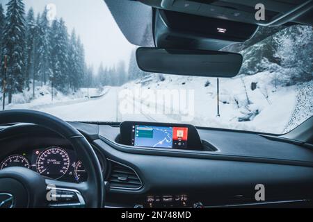 Italy, Veneto, Belluno, a Mazda Motor Corp. CX-30 crossover sport utility vehicle (SUV), inside view, car cockpit, driving on snowy mountain road Stock Photo