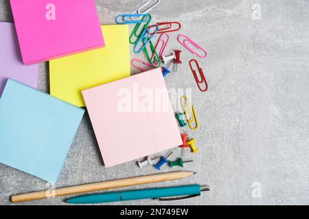 Bundles of multicolored stickers for written notes with chancellery on gray background Stock Photo
