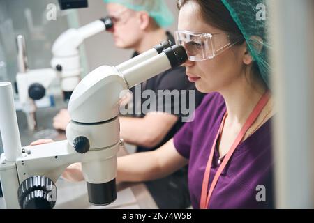 Laboratory staff in special glasses look through microscopes Stock Photo