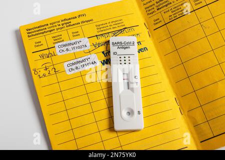 Vaccination card opened with entry of last Corona vaccinations, basic immunization, Rapid SARS-CoV-2 antigen test cassette with negative test result, Stock Photo