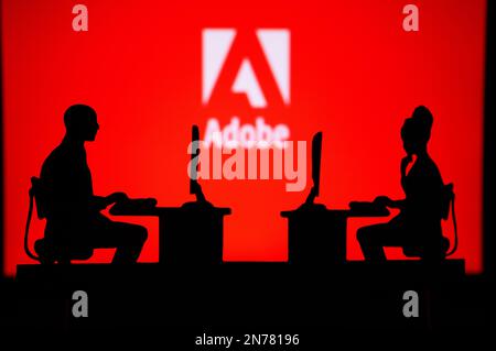 UK, LONDON. JANUARY 30, 2023: Adobe. Collaboration Leads to Progress: Two Developers Working Together Under the Company's Logo Stock Photo