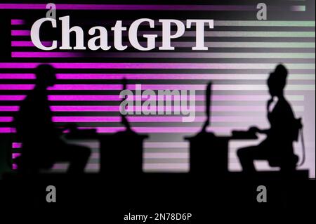 UK, LONDON. JANUARY 30, 2023: ChatGPT. Innovating the Future: Silhouette of Two Software Developers and the Company's Logo in the Background Stock Photo