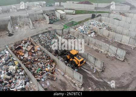 Skid steer loader moving garbage at the landfill site, before processing waste material, sorting, treatment, or recycling Stock Photo