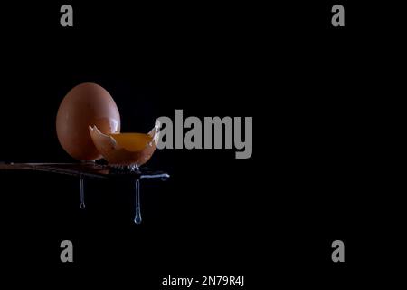 Egg with yolk and drops on the edge of a wooden table Stock Photo