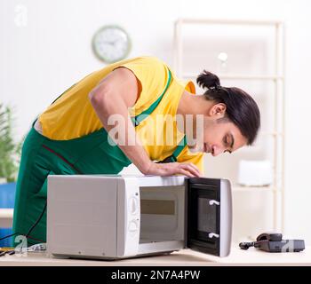 The young repairman repairing microwave in service centre Stock Photo