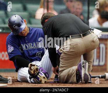 Colorado Rockies' Charlie Blackmon, left, shows to trainer Scott Gehret  where a foul ball hit his batting helmet as he stood in the on-deck circle,  during the third inning of the team's