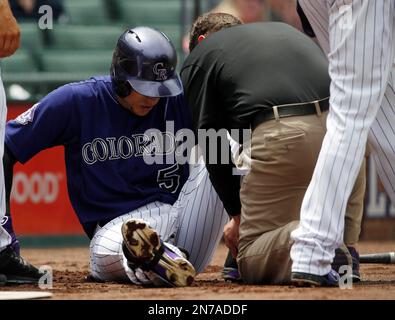 Colorado Rockies' Charlie Blackmon, left, shows to trainer Scott Gehret  where a foul ball hit his batting helmet as he stood in the on-deck circle,  during the third inning of the team's