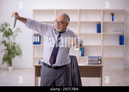 Old employee doing sport exercises during break Stock Photo