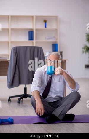Old employee doing sport exercises during break Stock Photo