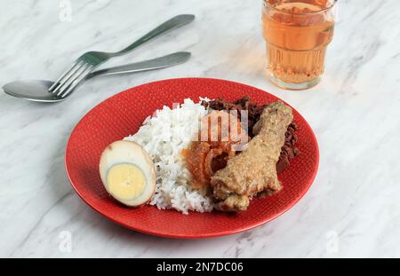 Nasi Gudeg on Red Plate. Gudeg Yogyakarta is Traditional Young Jackfruit Stew with Sweet Taste, Usually served with Boiled Egg, Chicken, and Krecek Stock Photo