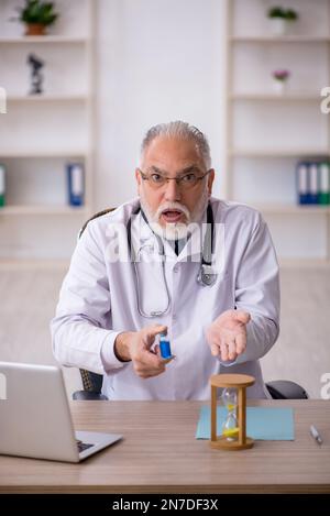 Old doctor in time management concept Stock Photo