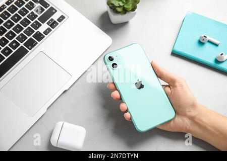 MYKOLAIV, UKRAINE - JULY 10, 2020: Woman holding Iphone 11 Green at table, top view Stock Photo