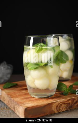 Tasty melon ball drink on wooden table against black background Stock Photo