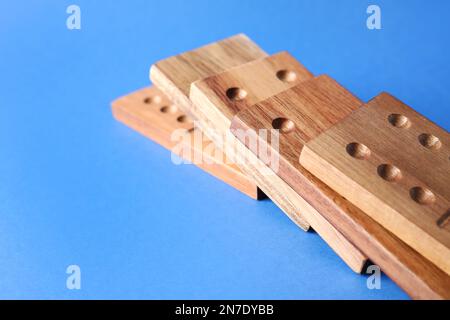 Fallen wooden domino tiles on blue background, closeup. Space for text Stock Photo