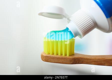 Applying toothpaste on brush against blurred background, closeup Stock Photo