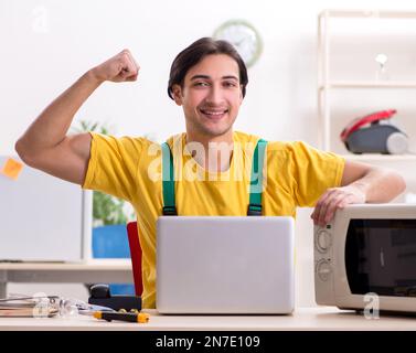 The young repairman repairing microwave in service centre Stock Photo