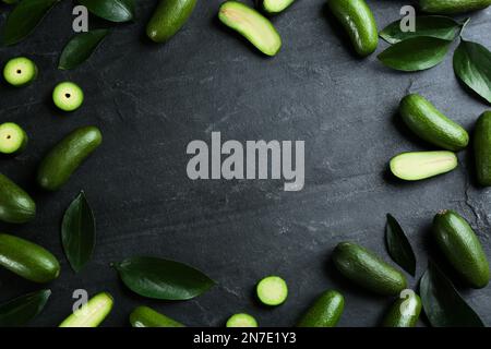 Frame made of fresh seedless avocados with green leaves on dark table, flat lay. Space for text Stock Photo