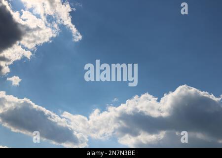Puffy clouds and light rays with a bright blue sky as the background create a heavenly effect. Stock Photo