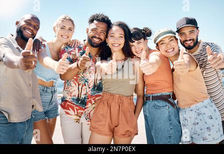 Find your happiness with people who understand you. a diverse group of friends standing outside together and showing a thumbs up. Stock Photo