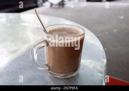 A hot chocolate malt beverage on an aluminium table. It is a typical Malaysian morning drink for energy and power. Stock Photo