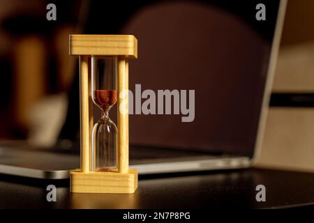Laptop and hourglass on the desktop. Time management concept. Stock Photo