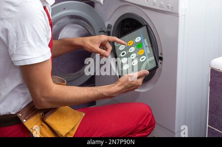 serviceman repairing washing machine looking at tablet Stock Photo