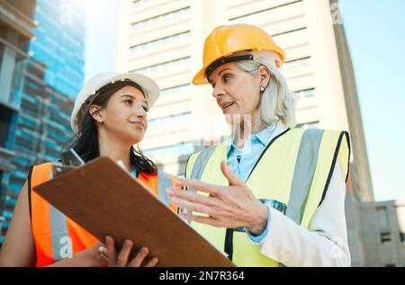 Do you think you can handle this. Low angle shot of two contractors standing outside together and having a discussion over a clipboard. Stock Photo