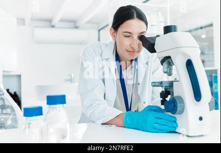 Experiments play many roles in science. a young scientist using a microscope in a lab. Stock Photo