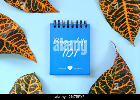 Happy life 101 motivational and inspirational guide written on blue notepad. Beautiful flat lay composition. Stock Photo