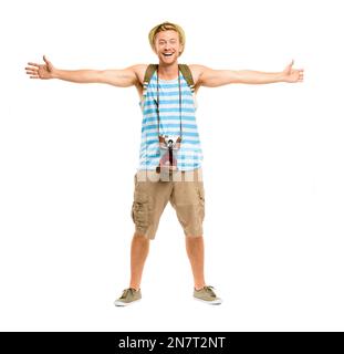 Its time to explore the world. Full length shot of a handsome young tourist standing alone in the studio with his arms outstretched in excitement. Stock Photo