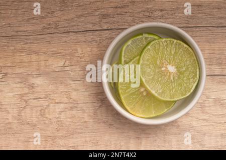 Sliced lemons in white cup on wooden background Stock Photo