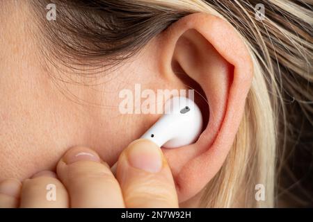 wireless white headphones in a girl's ear close-up Stock Photo