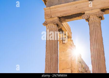 Sun hiding behind the columns of the Parthenon temple at Acropolis site on a sunny evening in Athens Greece Stock Photo