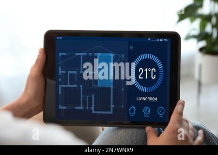 Woman using tablet to control heating system in house, closeup Stock Photo