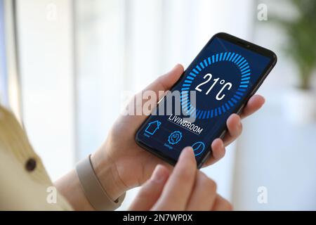 Man using smartphone to control heating system in house, closeup Stock Photo