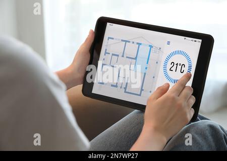 Woman using tablet to control heating system in house, closeup Stock Photo