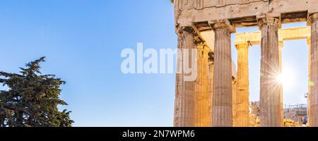 Sun hiding behind the columns of the Parthenon temple at Acropolis site on a sunny evening in Athens Greece Stock Photo