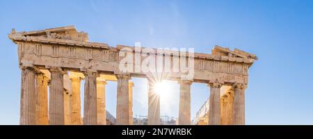 Sun hiding behind the columns of the Parthenon temple at Acropolis site on a sunny evening in Athens Greece Stock Photo