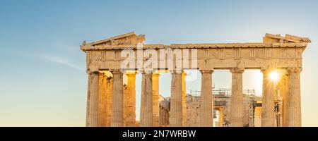 Sun hiding behind the columns of the Parthenon temple at Acropolis site on a sunny evening in Athens Greece Stock Photo