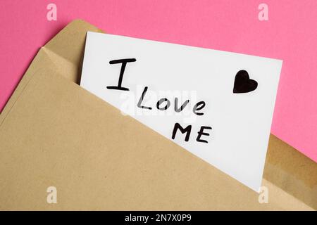 Paper note with phrase I Love Me in envelope on pink background, closeup Stock Photo