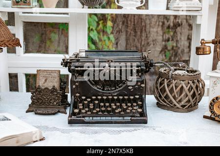 Vintage old fashioned typewriter machine on wooden desk next to window in light white shabby chic vintage french Provence country cottage interior Stock Photo